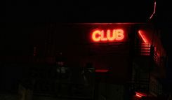 An einem dunklen Haus prangt in roter Neonschrift der Schriftzug "Club".